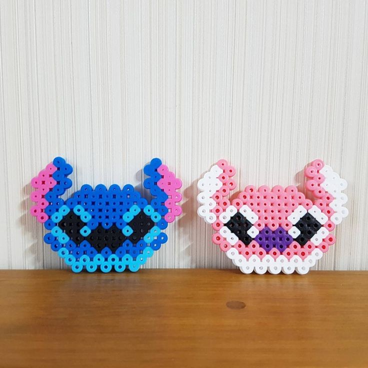 two perler beads are sitting next to each other on a wooden table in front of a white wall