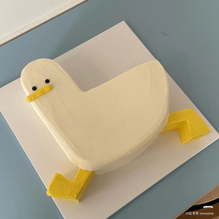 a cake shaped like a duck sitting on top of a white plate with yellow feet