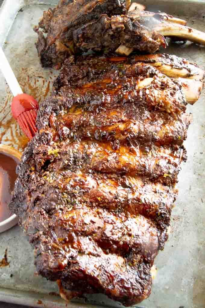 some meat is sitting on a tray next to sauces and a fork with a spoon in it