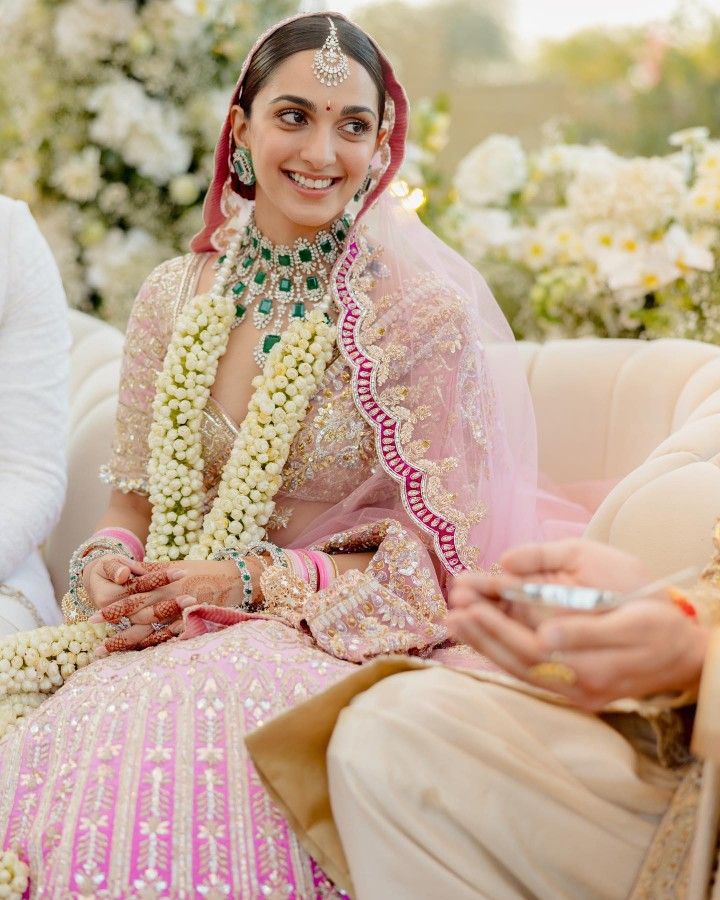 a bride and groom sitting on a white couch with flowers in the background at their wedding ceremony