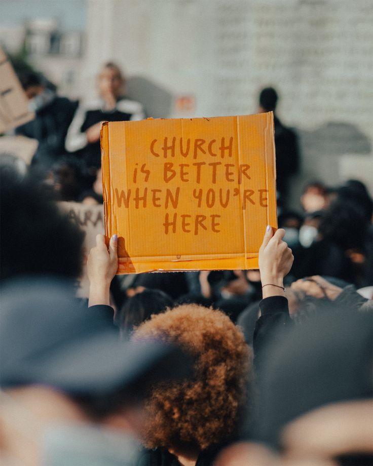 a person holding up a sign that says church is better when you're here