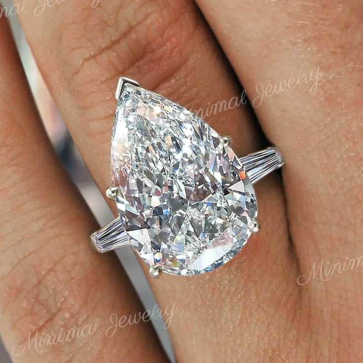 a woman's engagement ring with a pear shaped diamond in the center and baguetts on each side