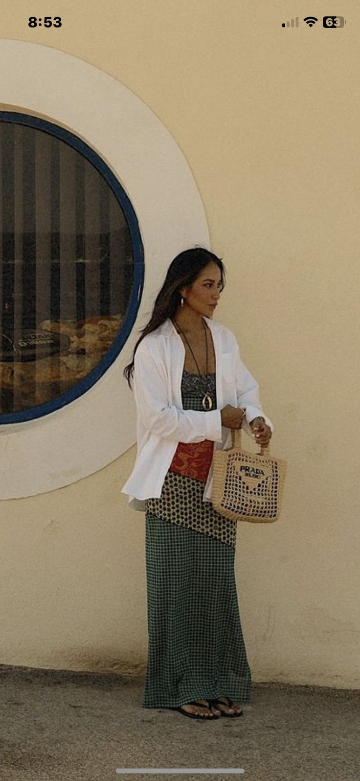 a woman standing in front of a building holding a bag