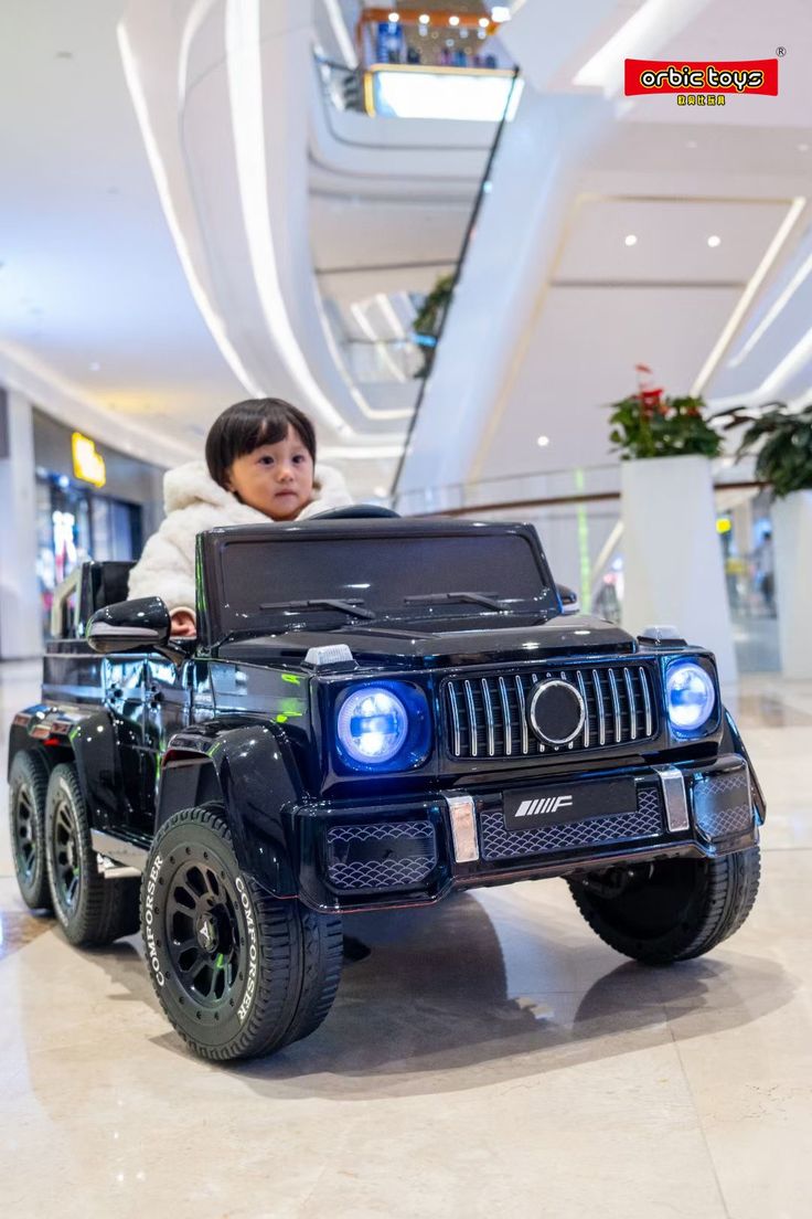 a young boy riding on top of a toy jeep