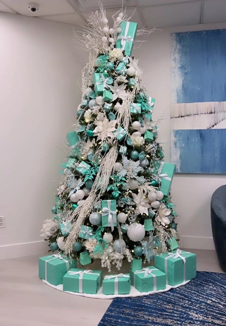 a decorated christmas tree with blue and white presents on it in an office lobby area