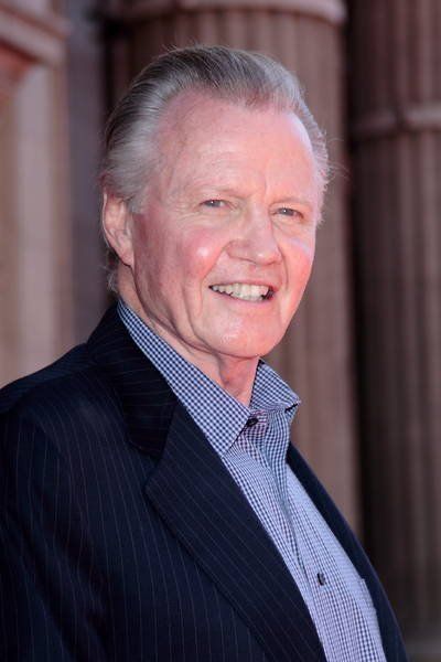 an older man wearing a suit and smiling at the camera with columns in the background