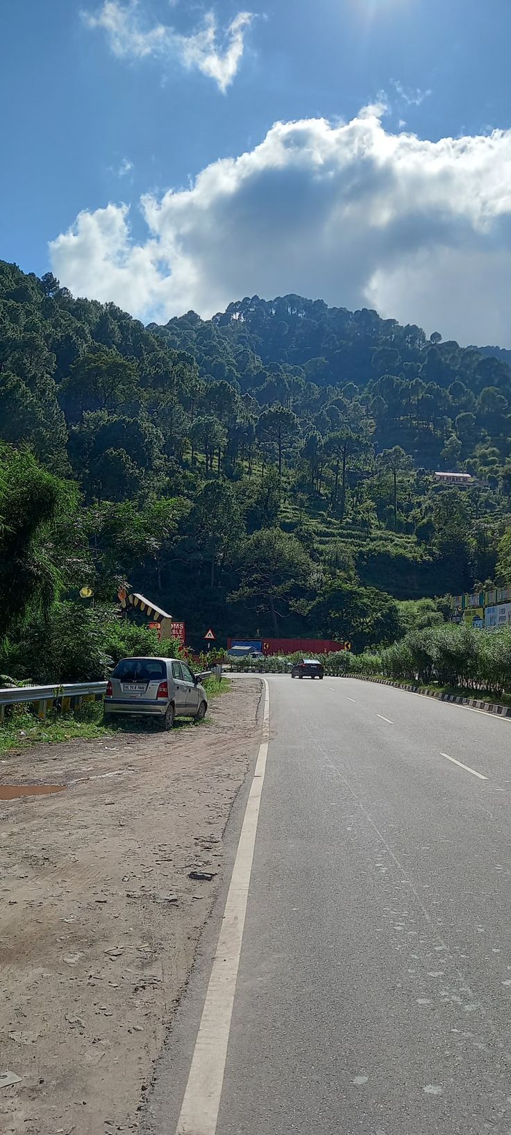 a car parked on the side of a road in front of a lush green mountain