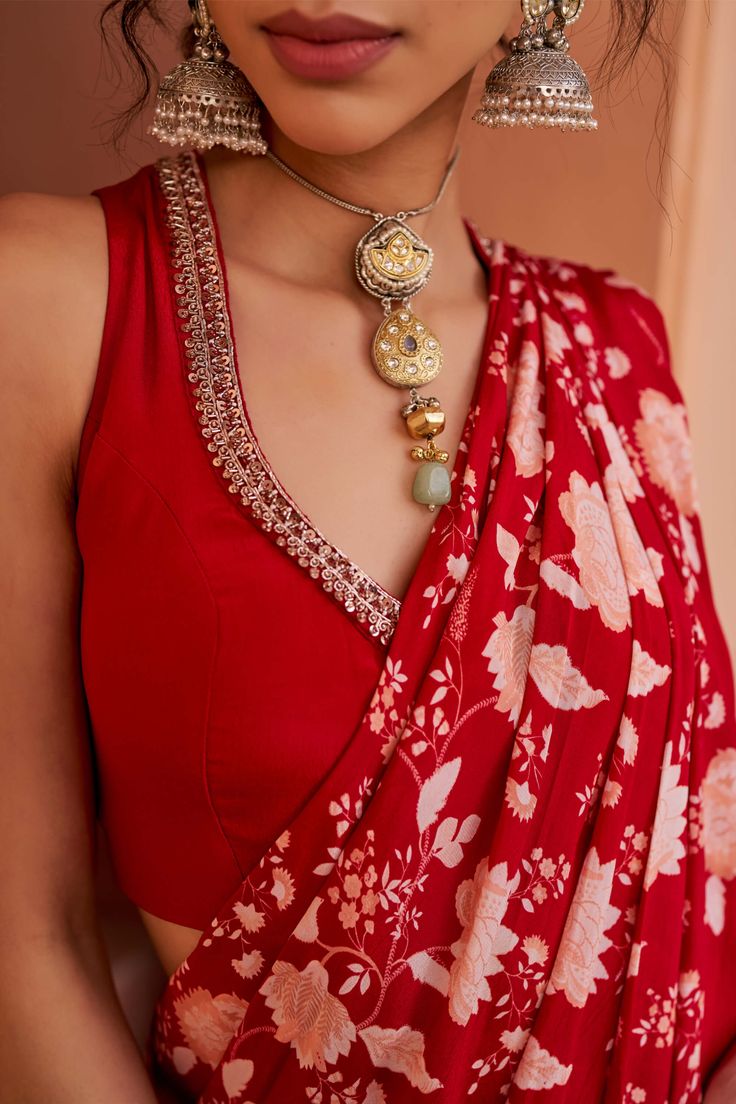 Introducing this striking red sleeveless blouse, adorned with intricate hand-embroidered detailing along the neckline for a touch of elegance. Paired seamlessly with red crepe pants featuring an attached printed drape, this ensemble exudes sophistication and style, perfect for making a bold statement at any occasion. Sleeveless Designer Blouse Designs, Red Saree With Sleeveless Blouse, Sleeveless Embroidered Blouse, Red Blouse Ideas, Crepe Blouse Design, Saree Blouse Styles Sleeveless, Sleeveless Blouse Ideas, Sleeve Less Blouse Designs, Sleeveless Blouse Designs Saree