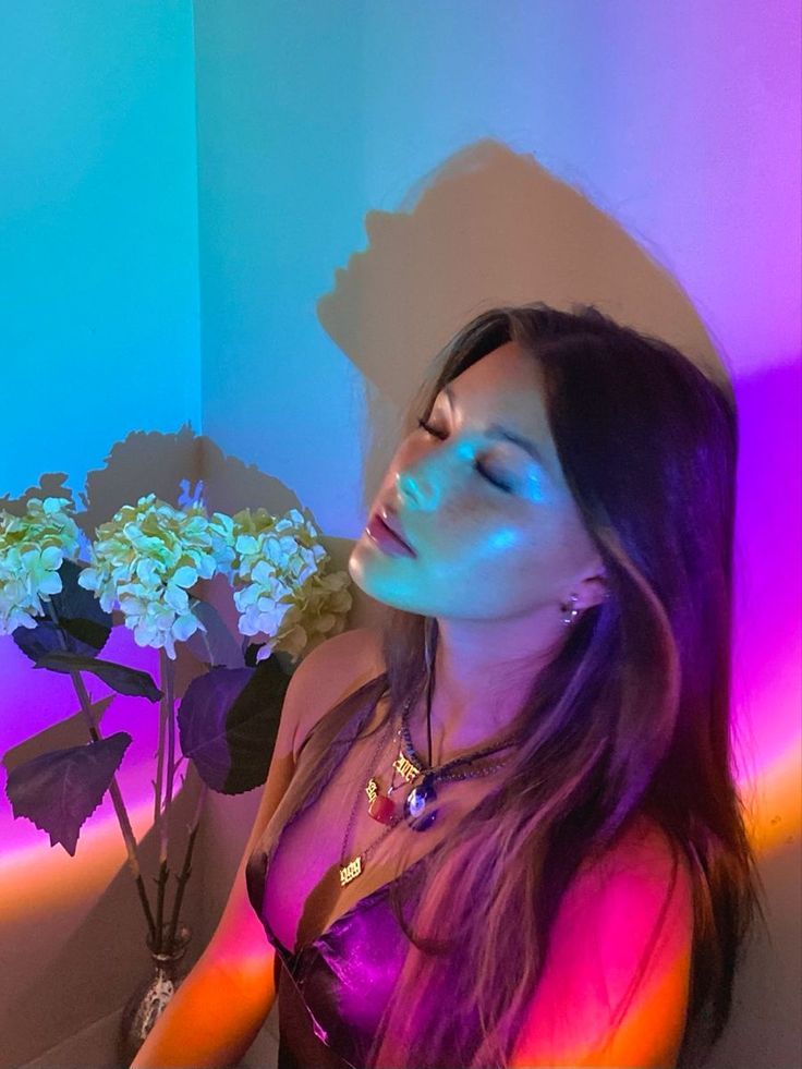 a woman sitting in front of a vase with flowers