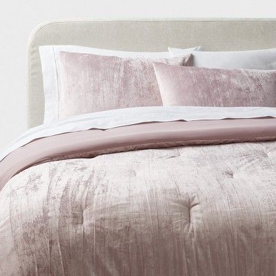 a bed that has some pillows on top of it and is made up with pink linens