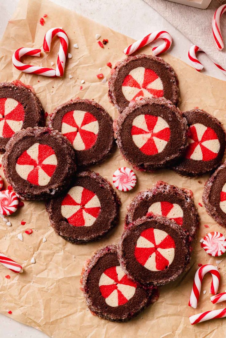 chocolate candy cookies with red and white icing on brown paper surrounded by candy canes