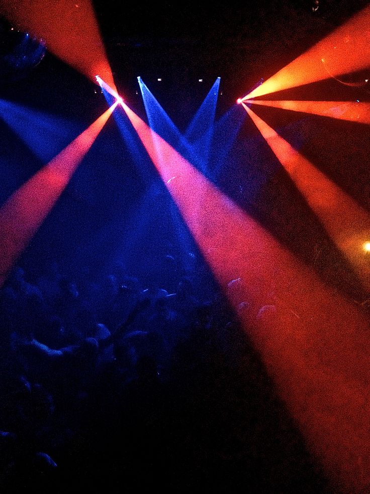 several spotlights are shining brightly on a concert stage as the crowd looks on from below