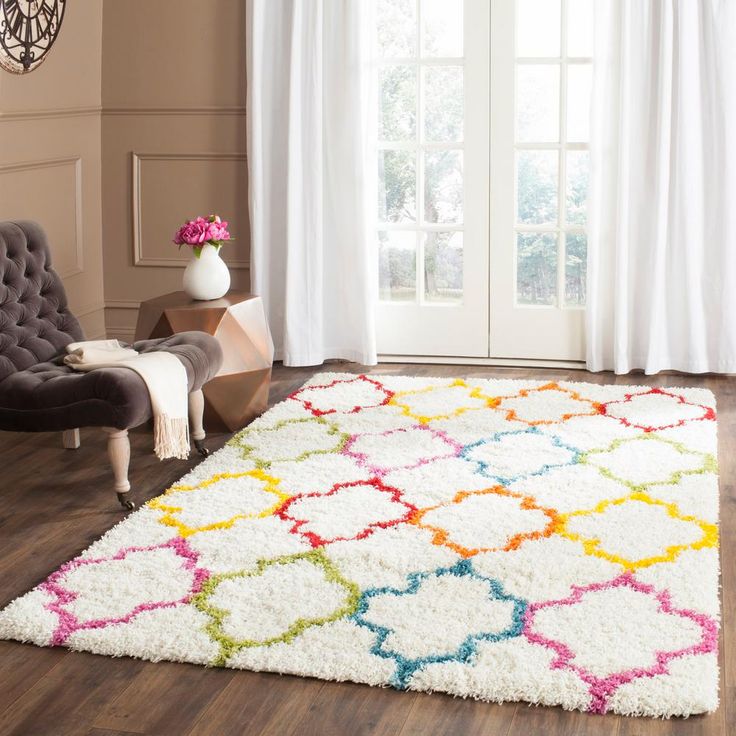 a white rug with multicolored circles on it in front of a chair and window