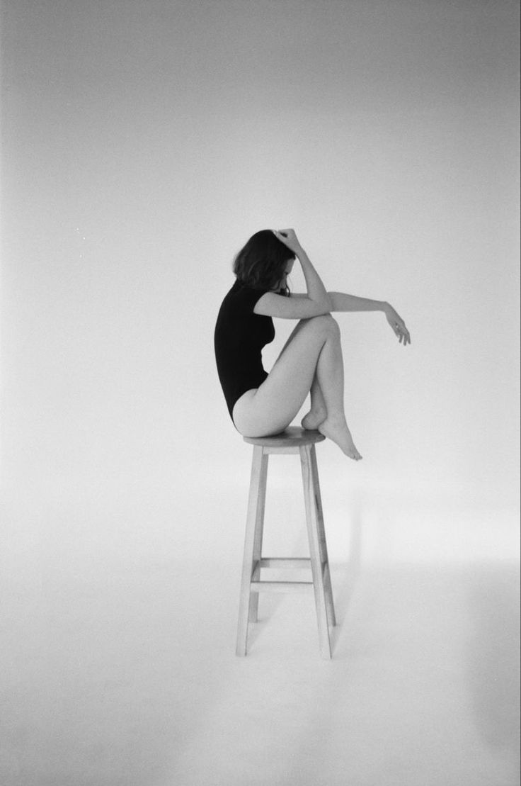 a black and white photo of a woman sitting on a stool