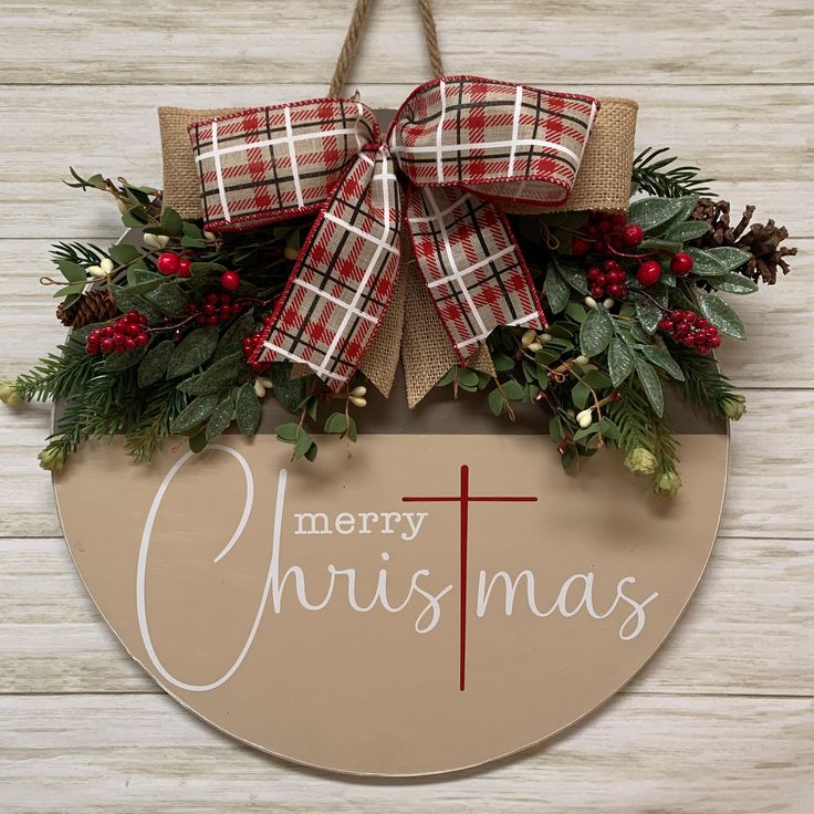 a merry christmas sign hanging on the side of a wooden wall with red berries and greenery