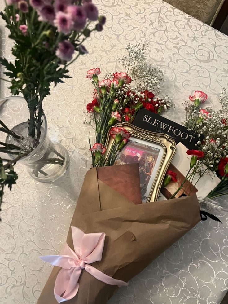 a bouquet of flowers sitting on top of a table next to a brown paper bag