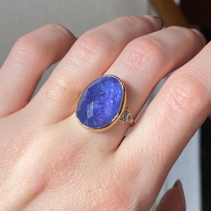 A regal Tanzanite is set in 14k yellow gold accented by two brilliant white diamonds. Finished with Emily's signature seagrass band in solid 14k yellow gold and handmade gold bead accents. Approximate stone size: 20mm x 12mm Approx CT weight: 13.85cts Approx diamond weight: .14cts Mohs hardness scale: 6-7 This one of a kind piece is handmade with love in Emily's Hudson Valley studio. If you have questions about sizing, shipping or need help deciding on your perfect piece please reach out to us! Mohs Hardness Scale, Hardness Scale, Local Jewelry, Handmade Gold, Hudson Valley, White Diamonds, Cocktail Ring, Cocktail Rings, Gold Beads