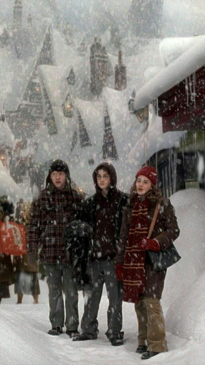 three people standing in the snow near a building