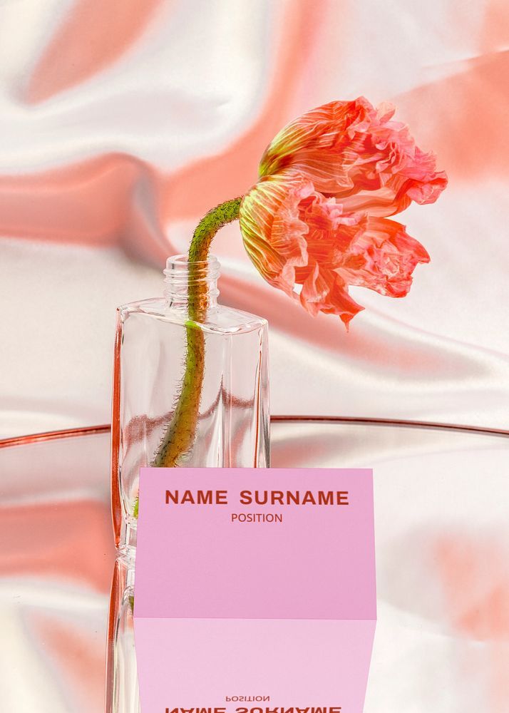 a pink flower in a vase next to a name card