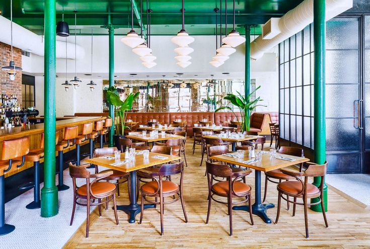 an empty restaurant with wooden tables and brown leather chairs, hanging lights and potted plants