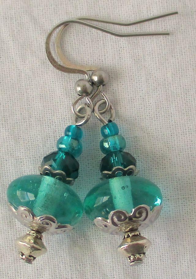 Add juicy color and shine to any summer outfit with these ocean green drop earrings. 1.5" in length, made with glass beads and steel accents/earhooks (no nickel, no lead). These ocean green drop earrings ship to you in a gift box, ready to give as a present or to keep and store. Back To Beaded Earrings Glass Drop Earrings For Gift, Turquoise Glass Earrings For Gift, French Hook Beaded Drop Earrings, Nickel-free Beaded Earrings For Gifts, Nickel-free Beaded Drop Earrings As Gift, Nickel-free Beaded Earrings As Gift, Nickel-free Drop Beaded Earrings As Gift, Nickel-free Round Bead Earrings As Gift, Silver Teardrop Beaded Earrings For Gift