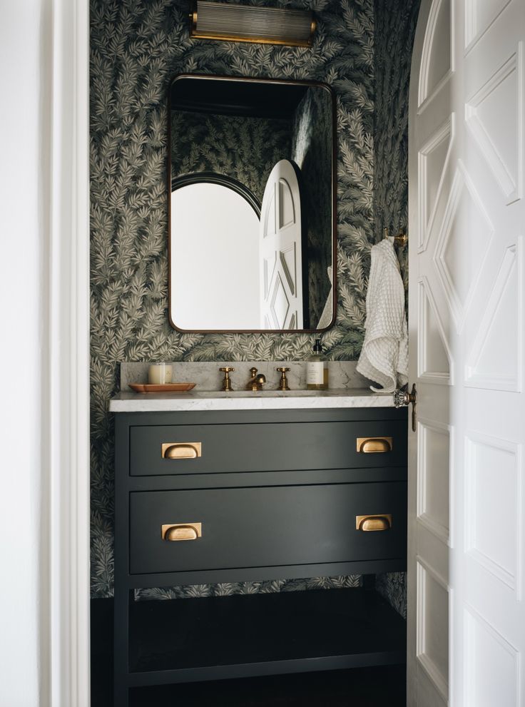 a bathroom with a sink, mirror and wallpapered walls in black and white