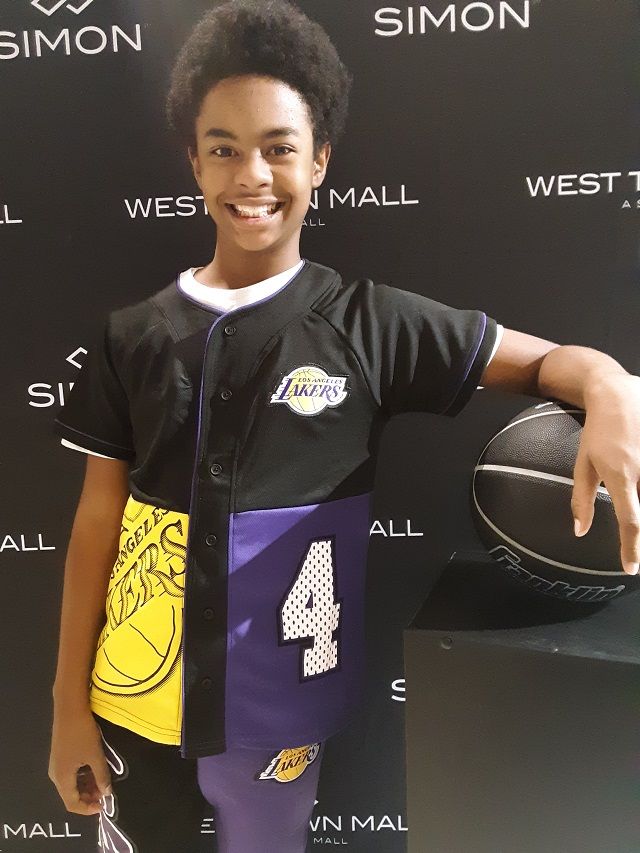 a young man holding a basketball in front of a black backdrop with the number 4 on it