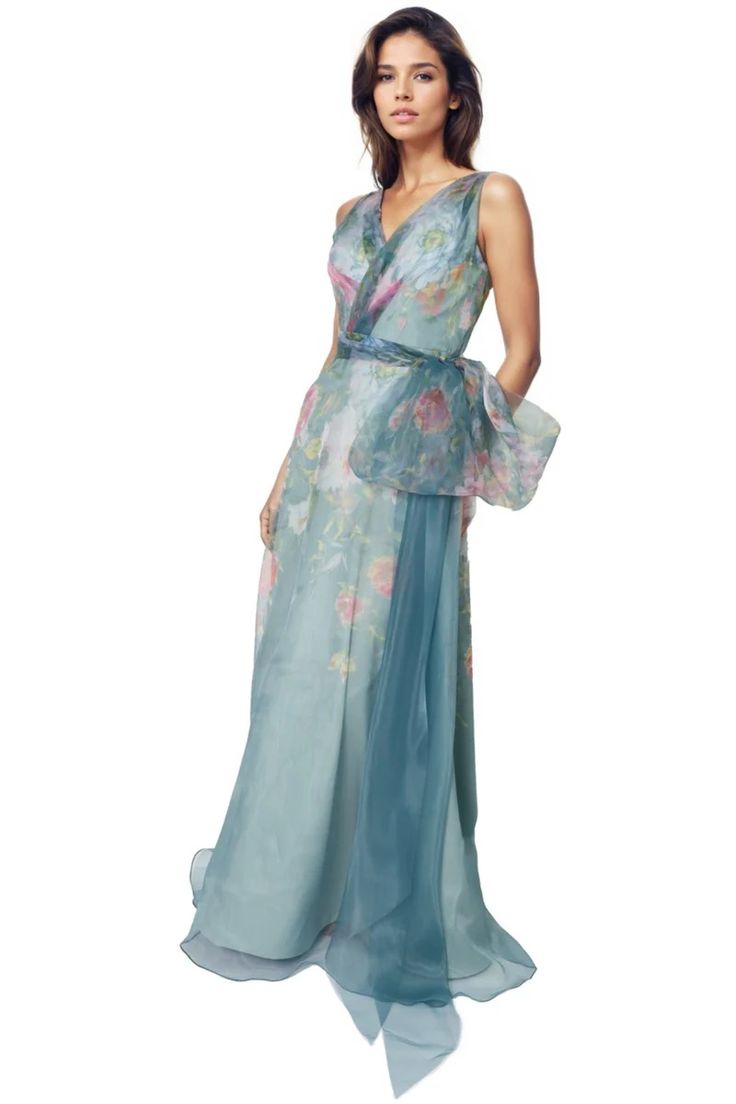 a woman in a long blue dress with flowers on the skirt and one hand on her hip