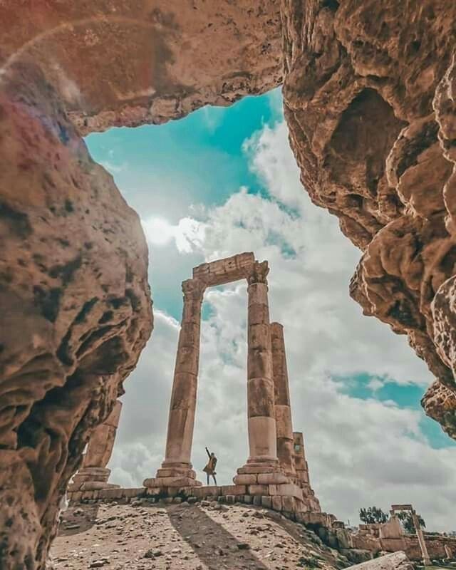 the ancient ruins are surrounded by large rocks and boulders, with one person standing in between them