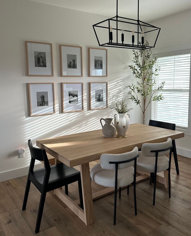 a dining room table with chairs and pictures on the wall