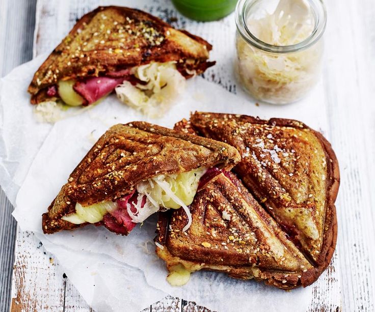 two grilled sandwiches sitting on top of paper next to a jar of ice cream