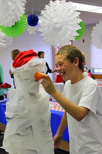 a young man is decorating a snowman with paper balls and tissue pom poms