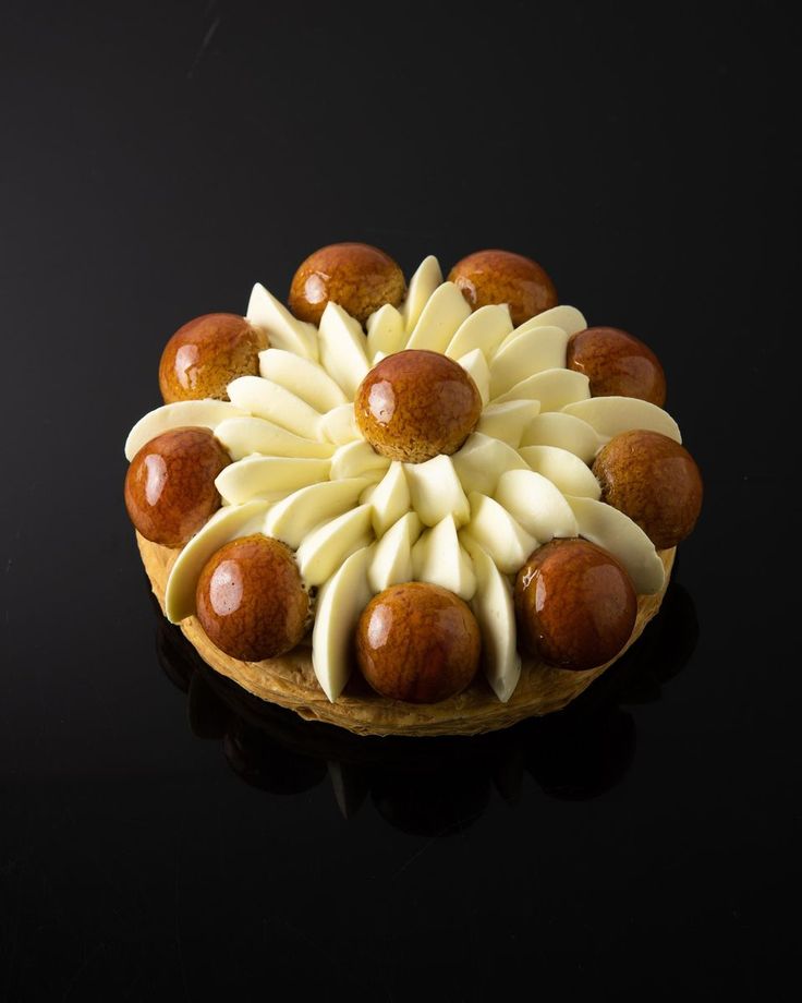 a cake with white and brown icing on a black surface, topped with apples