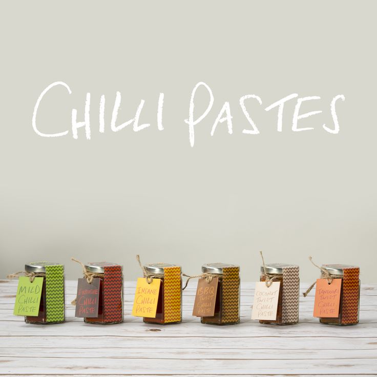 five small jars with labels on them sitting in front of a wall that says chilli pastes