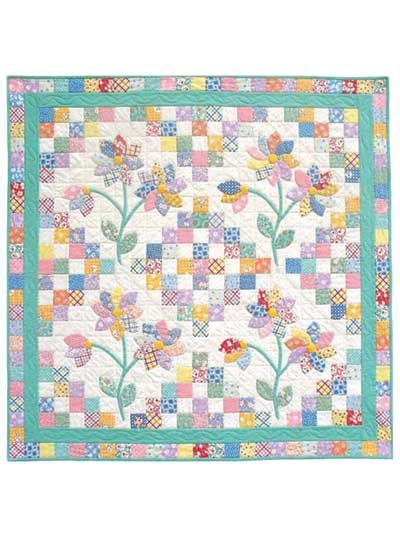 a quilted wall hanging with flowers and leaves on the front, in pastel colors