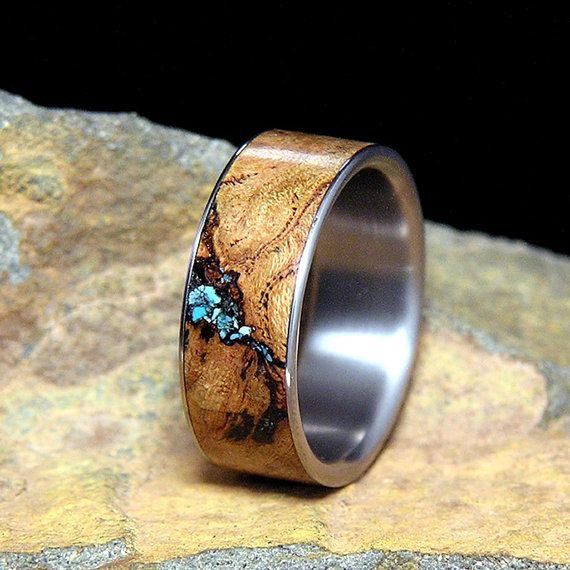 a wooden ring with blue flowers inlayed to it's surface on top of a rock