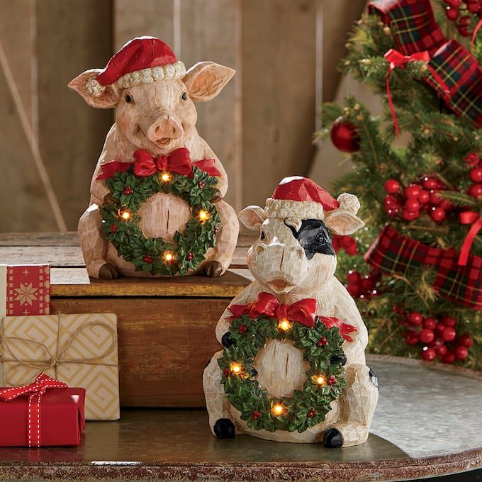 two pig figurines sitting next to each other with christmas wreaths on them