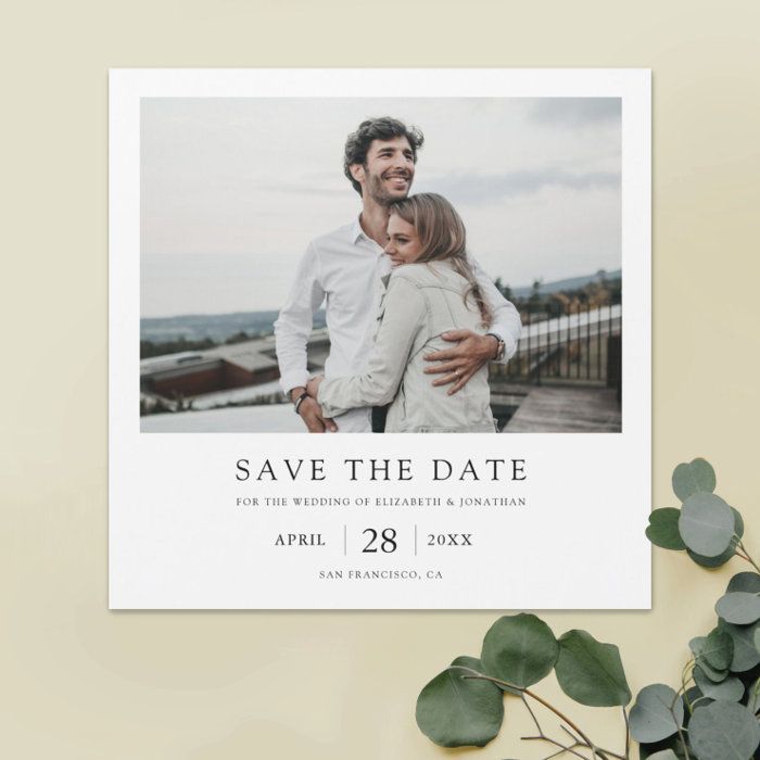 the save the date card is displayed on top of a table next to eucalyptus leaves