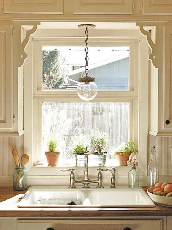 a kitchen sink sitting under a window next to a potted plant on top of a counter