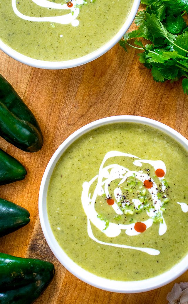 two white bowls filled with soup next to green peppers