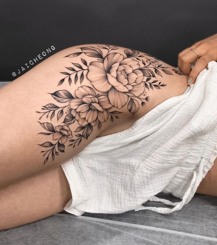 a woman's thigh with black and white flowers on the side, while she is laying down