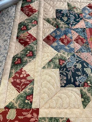 a close up of a quilted table runner with flowers on the border and red, green, blue, and white colors