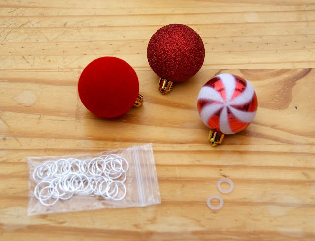 two red and white ornaments sitting on top of a wooden table next to paper clips