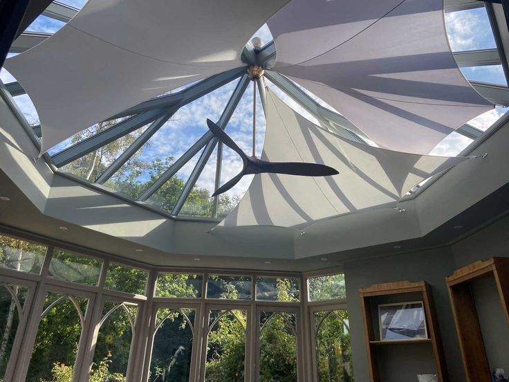 the inside of a sun room with large windows and an open ceiling fan hanging from the ceiling