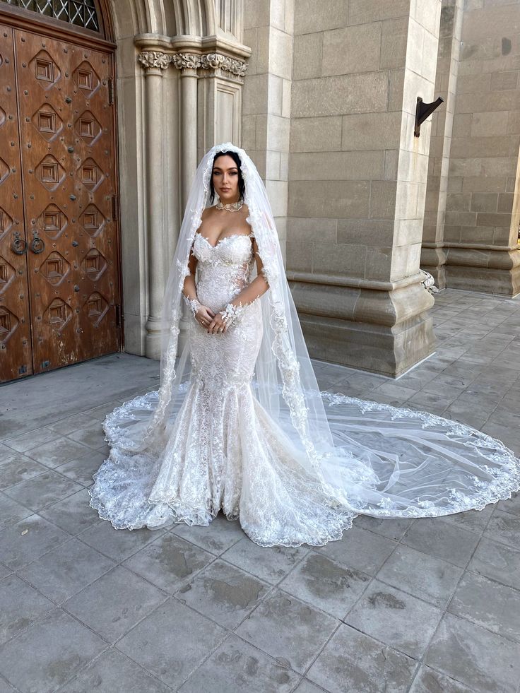 a woman in a wedding dress standing on the ground with a veil over her head