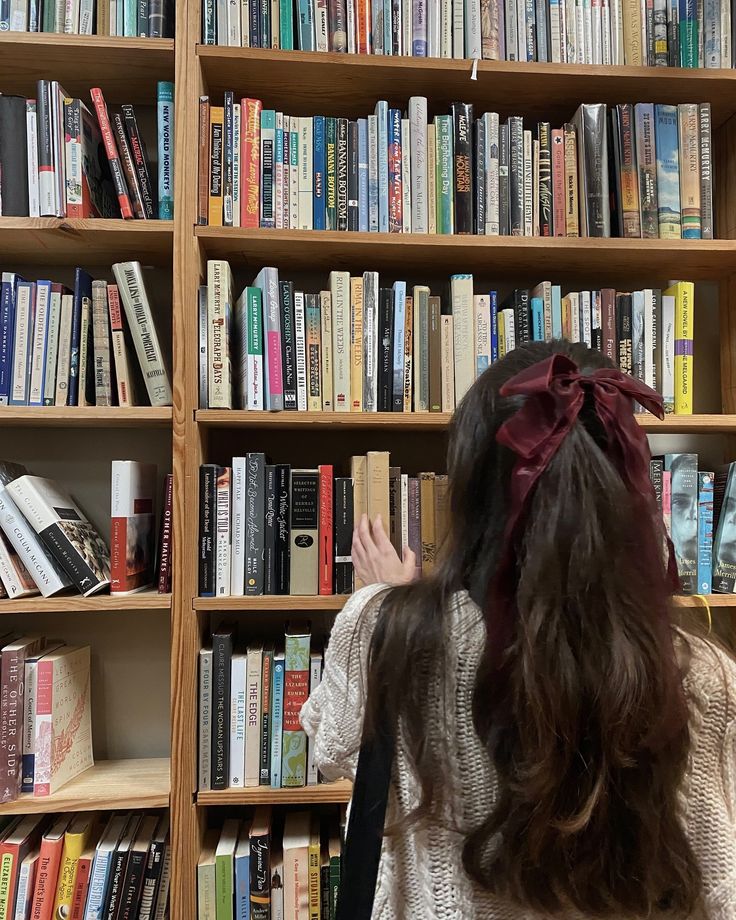 a woman standing in front of a book shelf filled with books