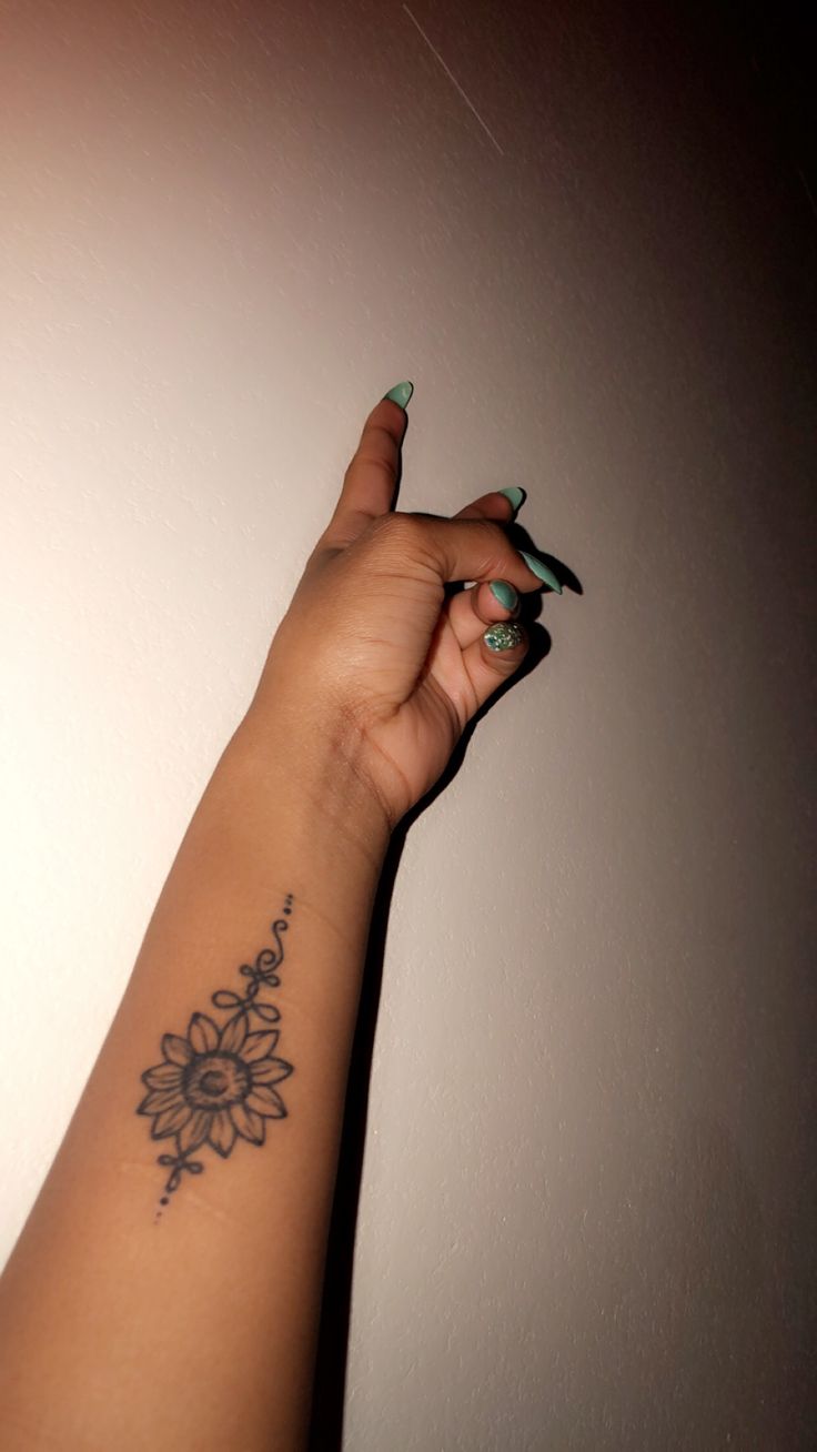 a woman's arm with a flower tattoo on the left side of her arm