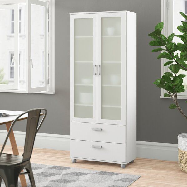 a white cabinet sitting in the middle of a room next to a table and chairs