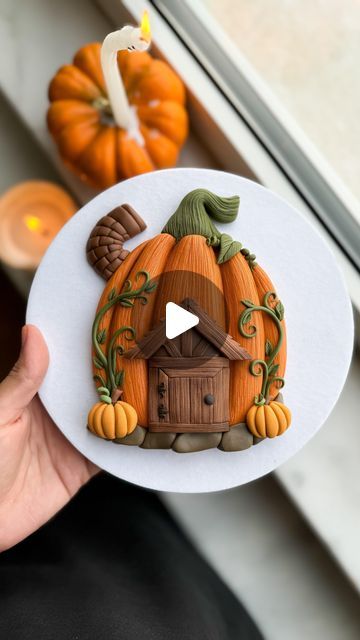 a person holding up a paper cut out of a house with pumpkins in the background