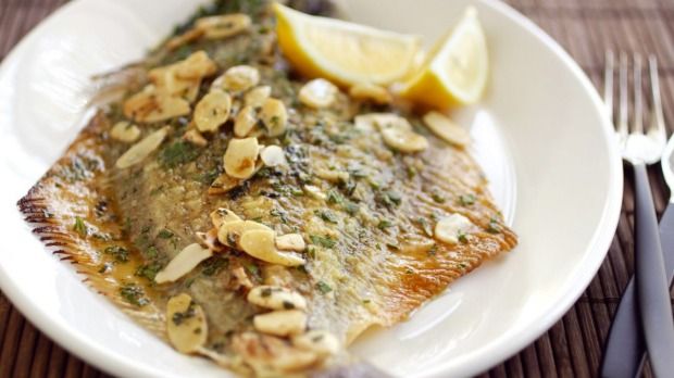 a white plate topped with fish and lemon wedges